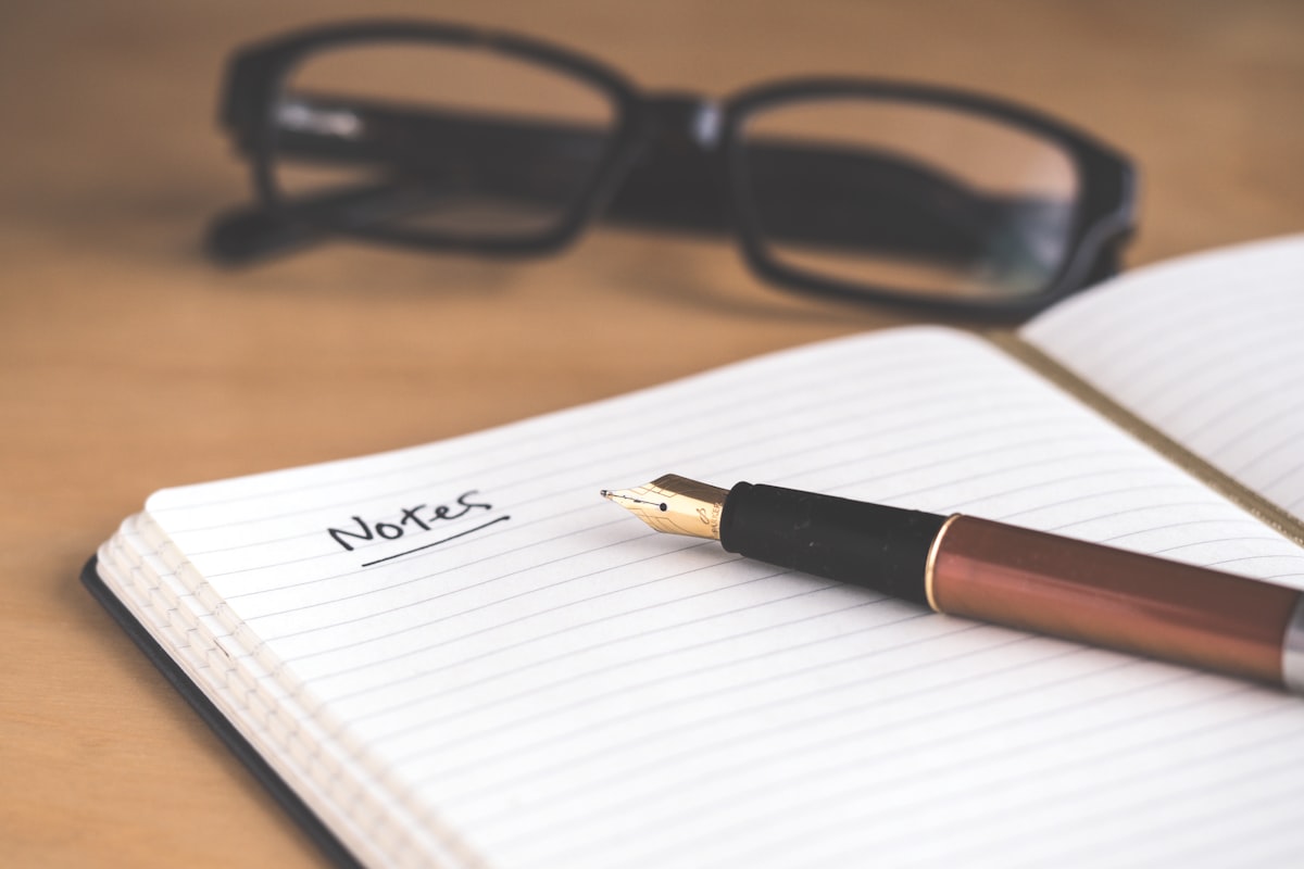 Open notebook and fountain pen on a wooden writing desk