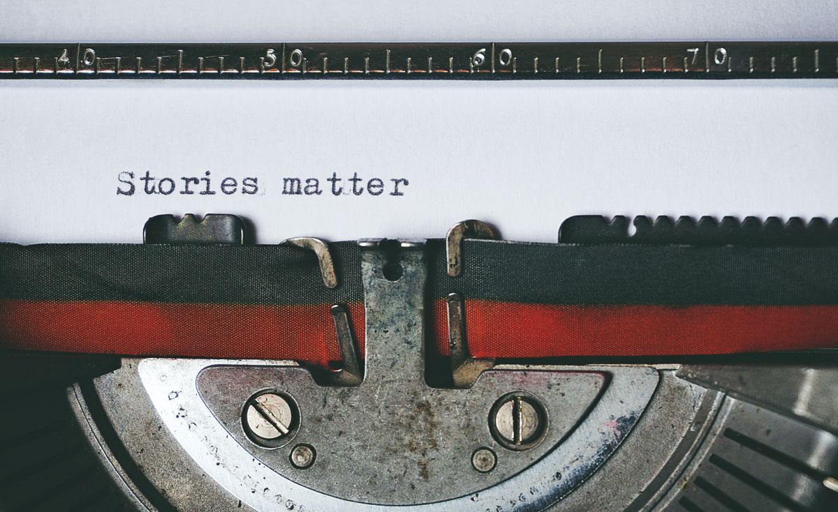 Hand writing in a notebook under a desk lamp