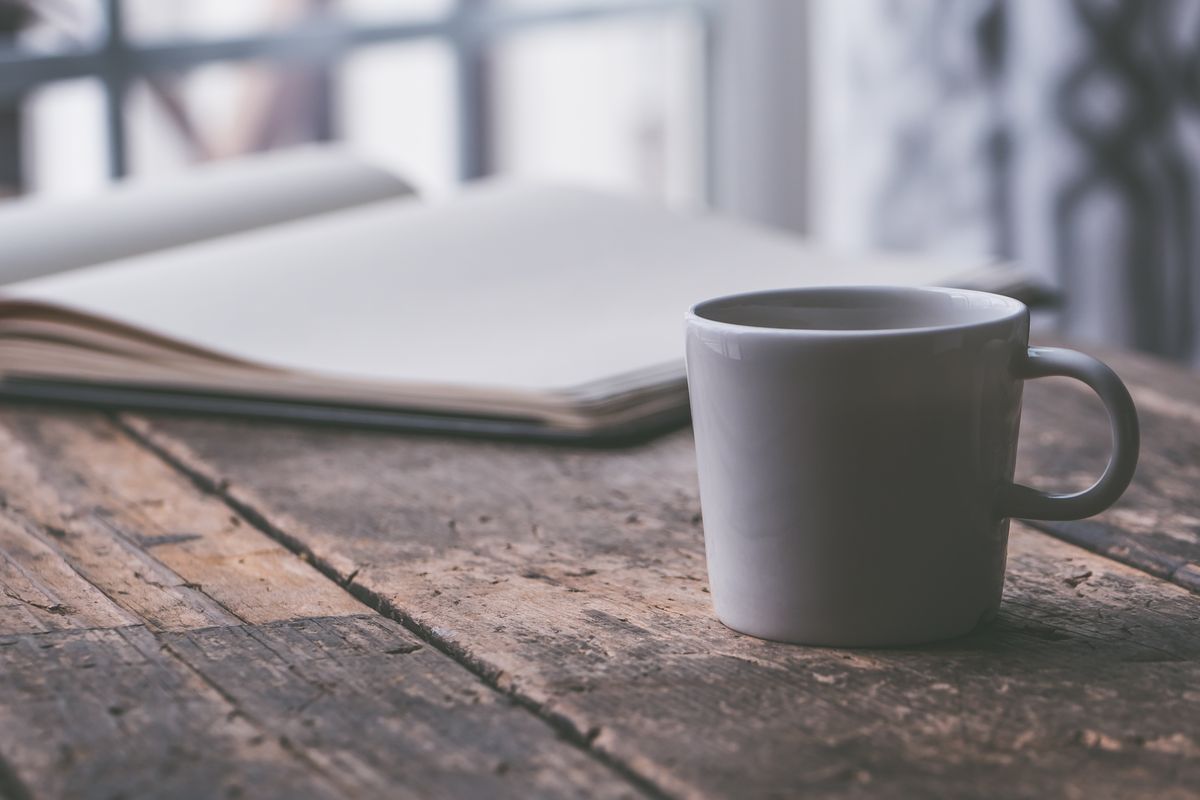 Tea cup and journal on a kitchen table in early light
